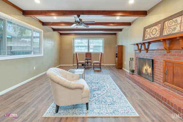 living room with ceiling fan, plenty of natural light, wood-type flooring, and a brick fireplace