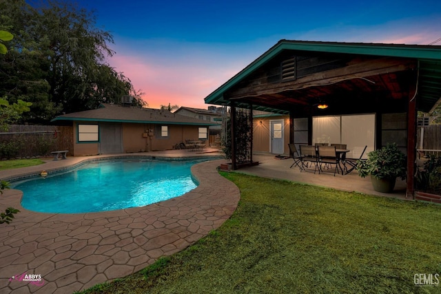 pool at dusk featuring a patio area and a yard