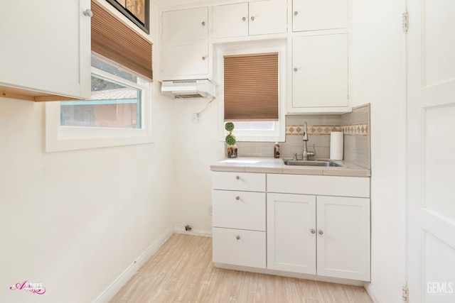 kitchen with light hardwood / wood-style flooring, tasteful backsplash, white cabinetry, and sink