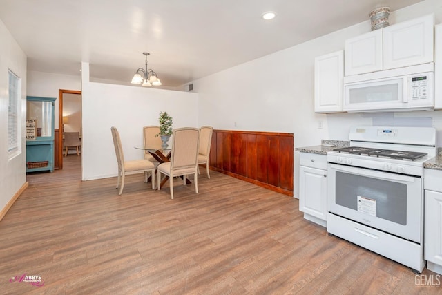 kitchen featuring white appliances, an inviting chandelier, white cabinets, hanging light fixtures, and light hardwood / wood-style flooring