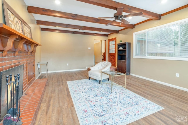 sitting room featuring beam ceiling, ceiling fan, a fireplace, and light hardwood / wood-style floors