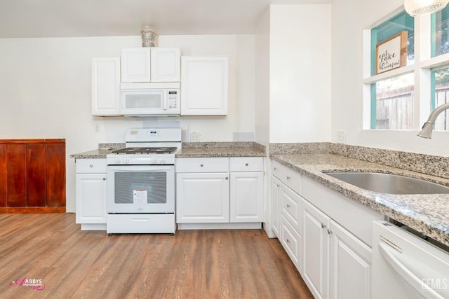 kitchen featuring white appliances, white cabinets, sink, light stone countertops, and light hardwood / wood-style floors