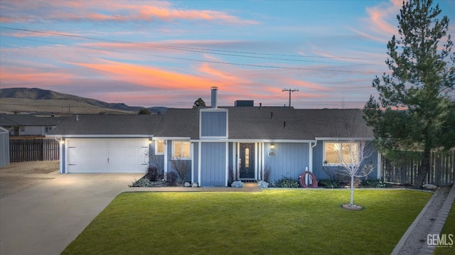 single story home featuring a garage and a lawn