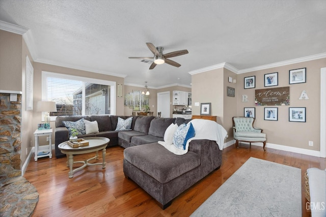 living room with hardwood / wood-style flooring, ornamental molding, ceiling fan with notable chandelier, and a textured ceiling