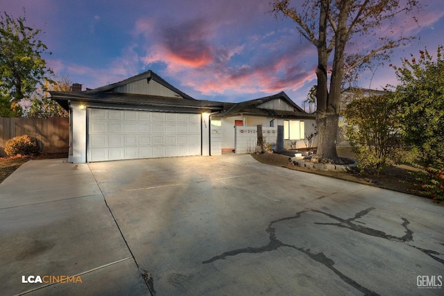 ranch-style house featuring concrete driveway, an attached garage, and fence