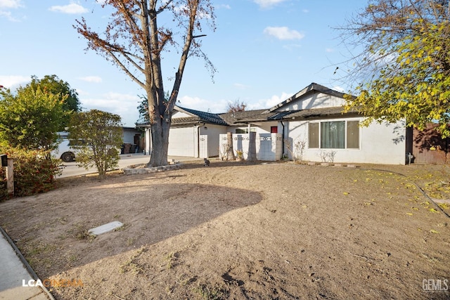 ranch-style home featuring a garage, fence, and stucco siding