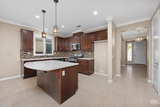 kitchen featuring visible vents, a center island, stainless steel appliances, crown molding, and light countertops