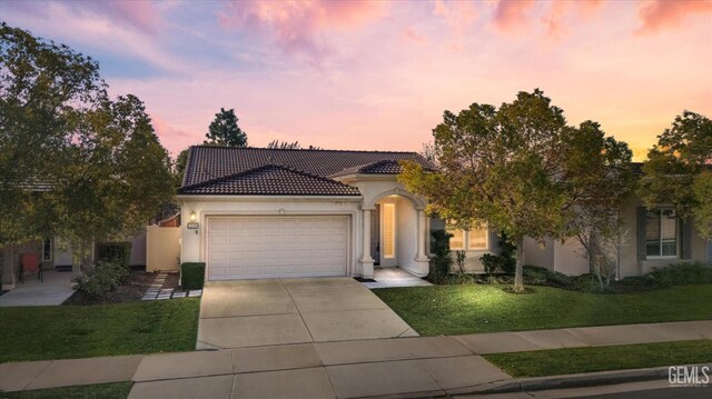 mediterranean / spanish-style home featuring a front lawn and a garage