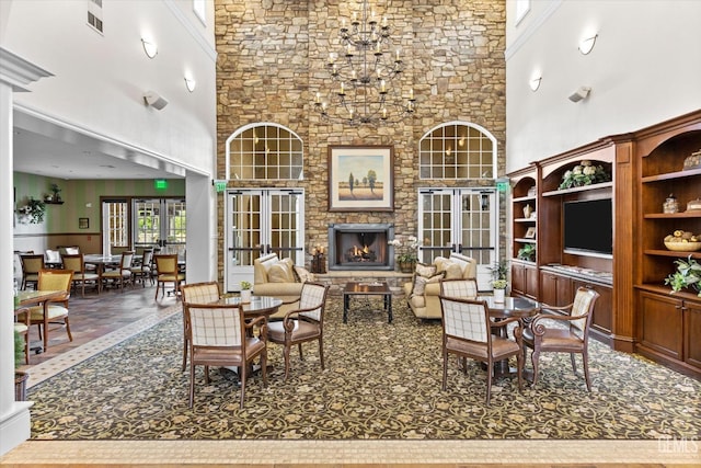 living room with visible vents, an inviting chandelier, a fireplace, crown molding, and a towering ceiling