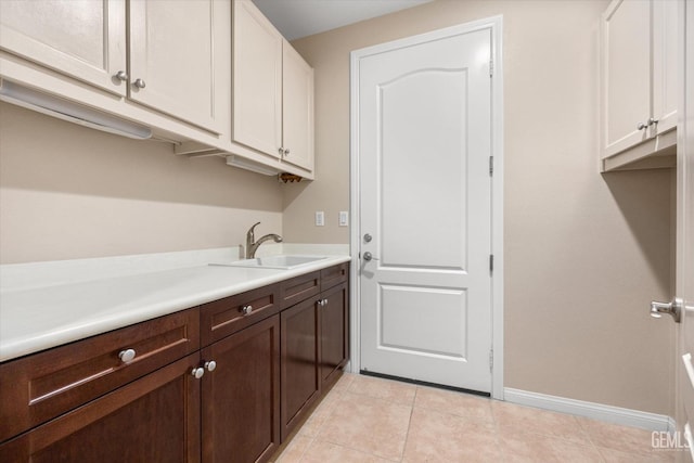 washroom with light tile patterned flooring, baseboards, and a sink