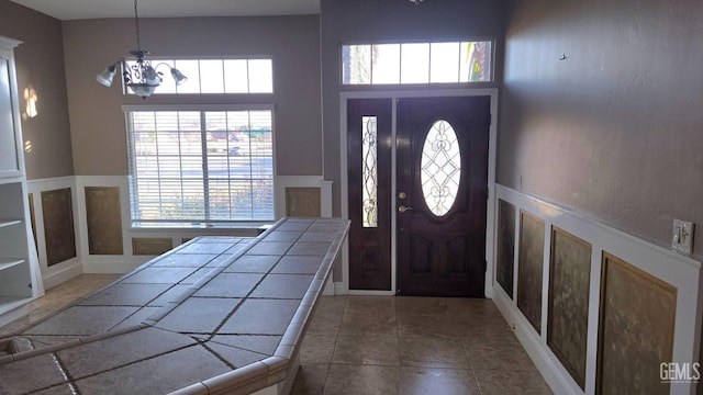 foyer entrance with an inviting chandelier, a towering ceiling, and dark tile patterned floors