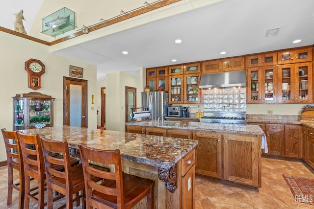 kitchen with a breakfast bar, a center island, stainless steel appliances, and light stone counters