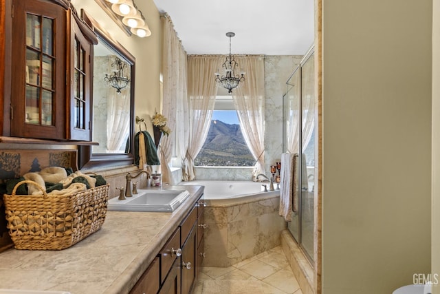 bathroom with vanity, an inviting chandelier, and separate shower and tub