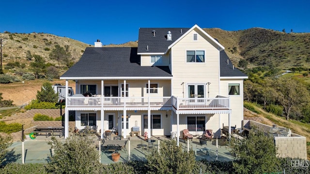 rear view of property featuring a mountain view, a patio, and a balcony