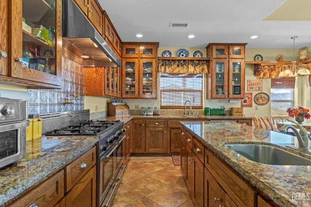 kitchen with stone countertops, decorative light fixtures, sink, and stainless steel range