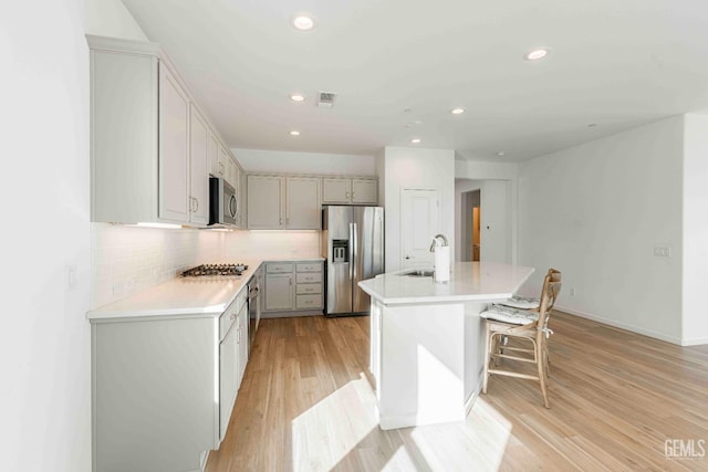 14209 Boon Way, Bakersfield, CA 93311 - kitchen with sink, a breakfast bar area, stainless steel appliances, a kitchen island with sink, and decorative backsplash