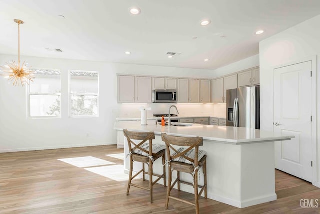 14209 Boon Way, Bakersfield, CA 93311 - kitchen with sink, hanging light fixtures, light wood-type flooring, appliances with stainless steel finishes, and an island with sink