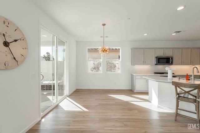 14209 Boon Way, Bakersfield, CA 93311 - kitchen with backsplash, a kitchen bar, hanging light fixtures, a notable chandelier, and light wood-type flooring