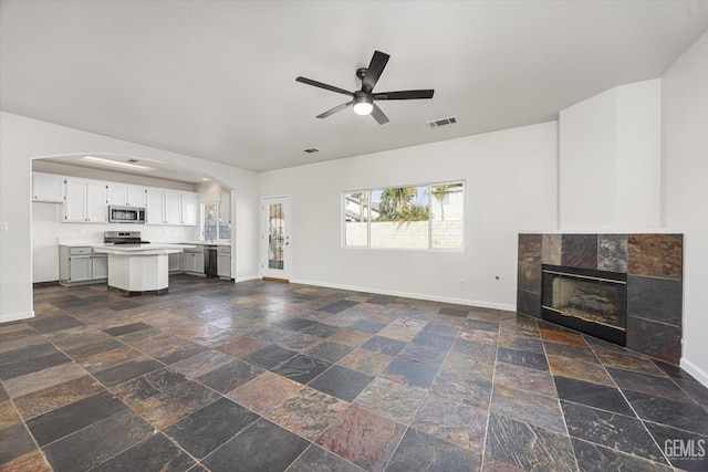 unfurnished living room featuring ceiling fan and a fireplace