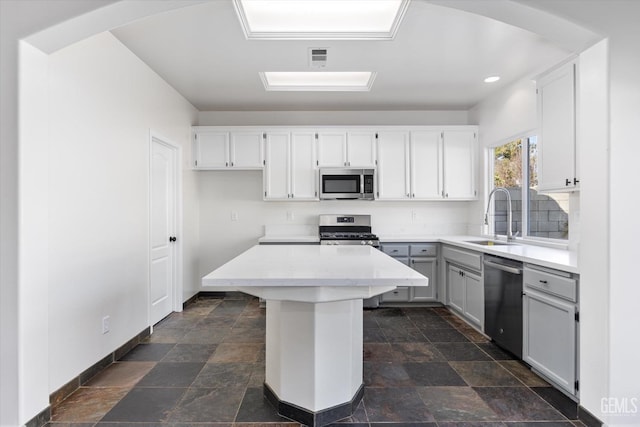 kitchen featuring stainless steel appliances, a center island, sink, and white cabinets