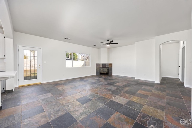 unfurnished living room featuring ceiling fan and a fireplace