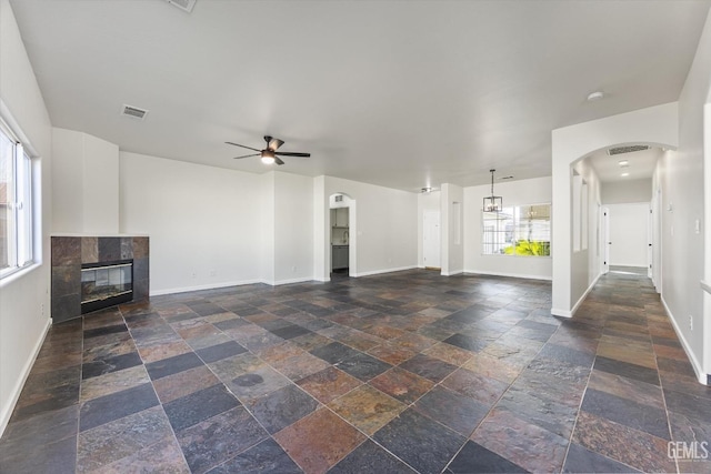 unfurnished living room featuring a tiled fireplace and ceiling fan