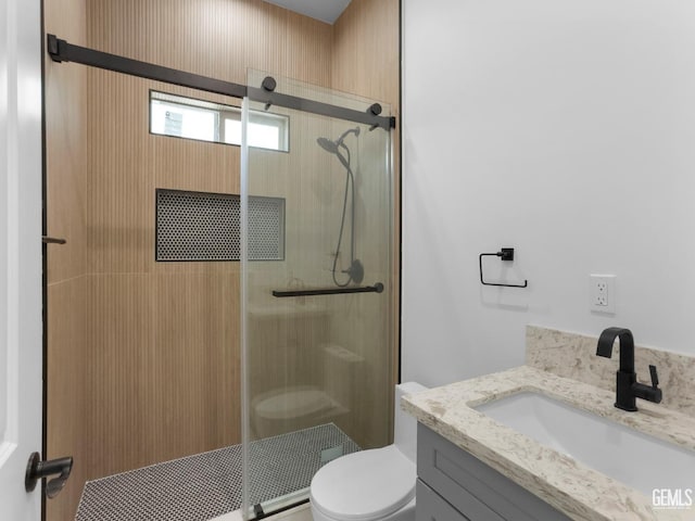 bathroom with a shower stall, toilet, and vanity