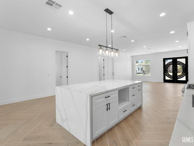 kitchen featuring light stone counters, recessed lighting, visible vents, baseboards, and open floor plan