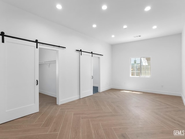 unfurnished bedroom featuring baseboards, a barn door, and recessed lighting