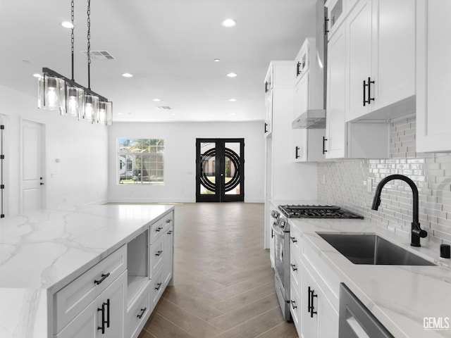 kitchen featuring white cabinetry, stainless steel range with gas cooktop, visible vents, and decorative backsplash