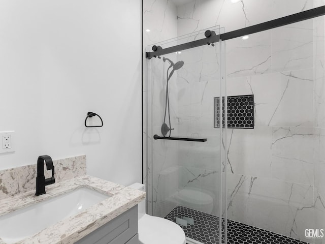 full bath featuring toilet, vanity, and a marble finish shower