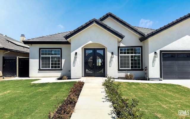 entrance to property with a garage, a tiled roof, a lawn, and stucco siding