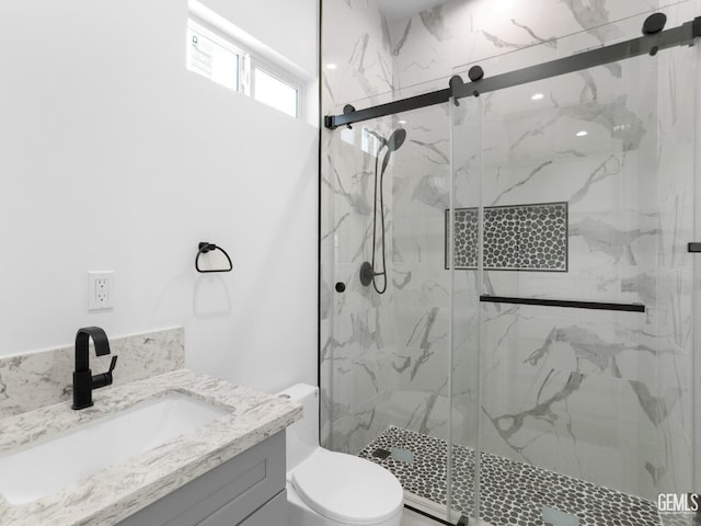 full bathroom with a marble finish shower, vanity, and toilet