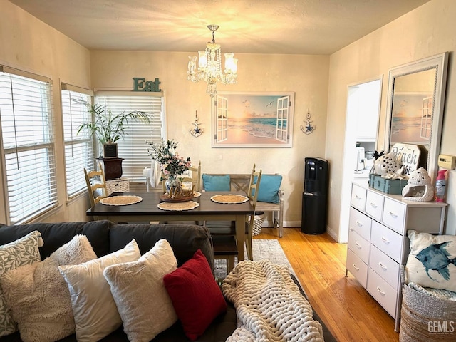 dining room with light wood-type flooring, a wealth of natural light, and a notable chandelier