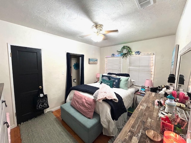 bedroom with hardwood / wood-style flooring, a textured ceiling, and ceiling fan