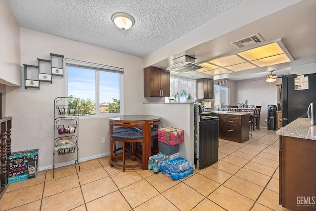 kitchen with black fridge, dark brown cabinets, a textured ceiling, ceiling fan, and light tile patterned flooring