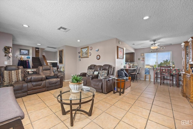 living room featuring a textured ceiling, ceiling fan, and light tile patterned flooring