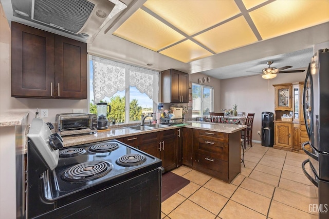 kitchen with kitchen peninsula, ceiling fan, sink, range with electric stovetop, and fridge