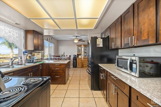 kitchen featuring sink, ceiling fan, light stone countertops, light tile patterned floors, and range