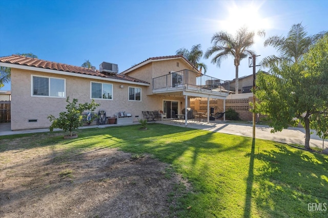 back of property with a yard, a balcony, cooling unit, and a patio area