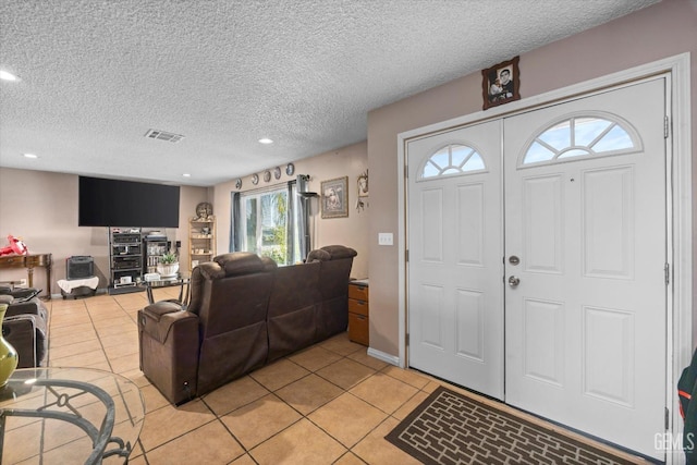 foyer entrance with light tile patterned floors and a textured ceiling