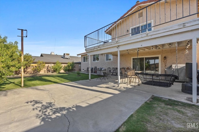 back of house with a lawn, a patio area, and a balcony