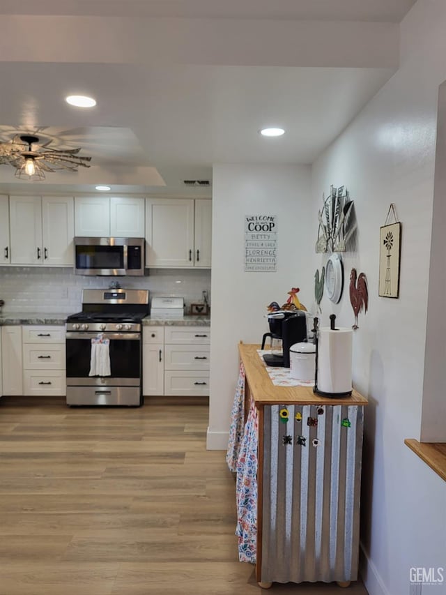 9101 Kern Island St, Bakersfield, CA 93307 - kitchen featuring appliances with stainless steel finishes, light wood-type flooring, white cabinetry, recessed lighting, and tasteful backsplash