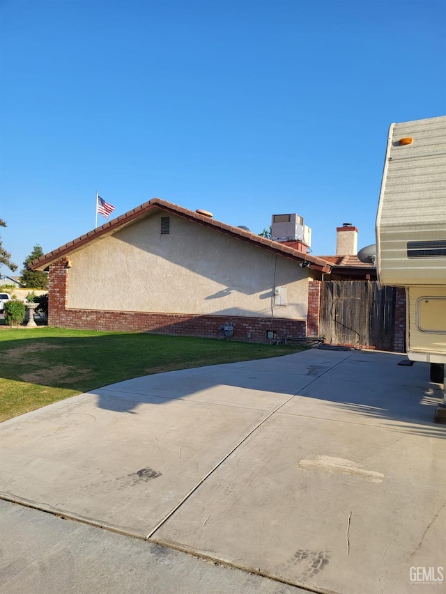 9101 Kern Island St, Bakersfield, CA 93307 - view of side of home with central AC, brick siding, and a patio area