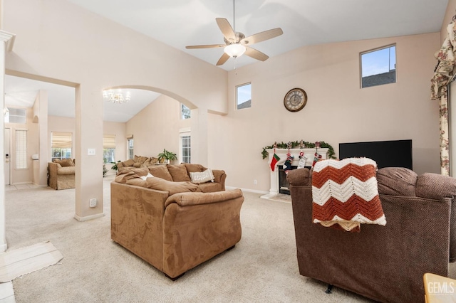 carpeted living room featuring ceiling fan with notable chandelier and vaulted ceiling