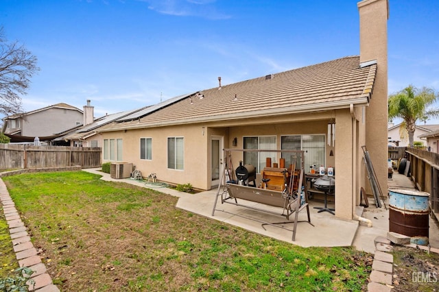 back of property with a lawn, a patio area, cooling unit, and solar panels