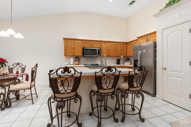 kitchen with decorative light fixtures, stainless steel appliances, light tile patterned floors, and tasteful backsplash