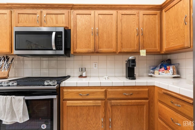 kitchen with tile countertops, backsplash, and stainless steel appliances