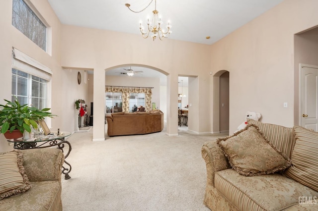 living room featuring ceiling fan with notable chandelier, a high ceiling, and carpet floors