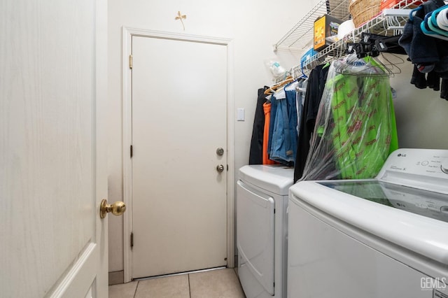 clothes washing area featuring washing machine and dryer and light tile patterned flooring